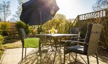 Terrasse mit Gartenmöbeln und Auflagen für ein gemütliches Sonnenfrühstück