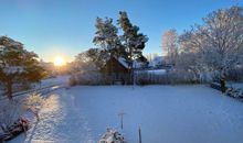 Sonnenaufgang über dem winterlichen Garten im Premiumhaus