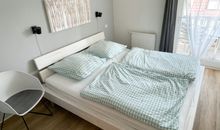 Das 1. Schlafzimmer mit einem Doppelbett und Zugang zum Balkon