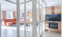 Glaswand als Raumtrennung von Wohnzimmer und Küche